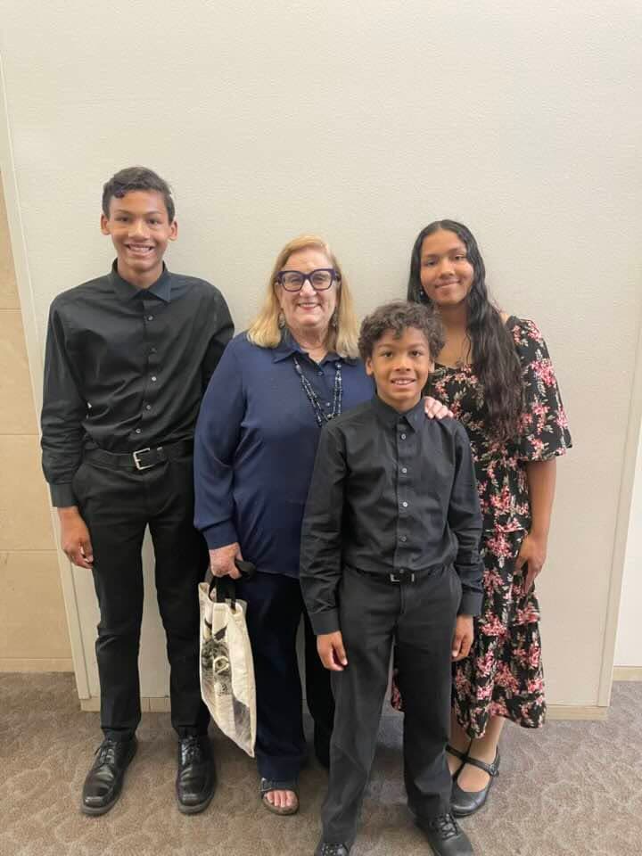 Three students dressed for a performance standing with their teacher.